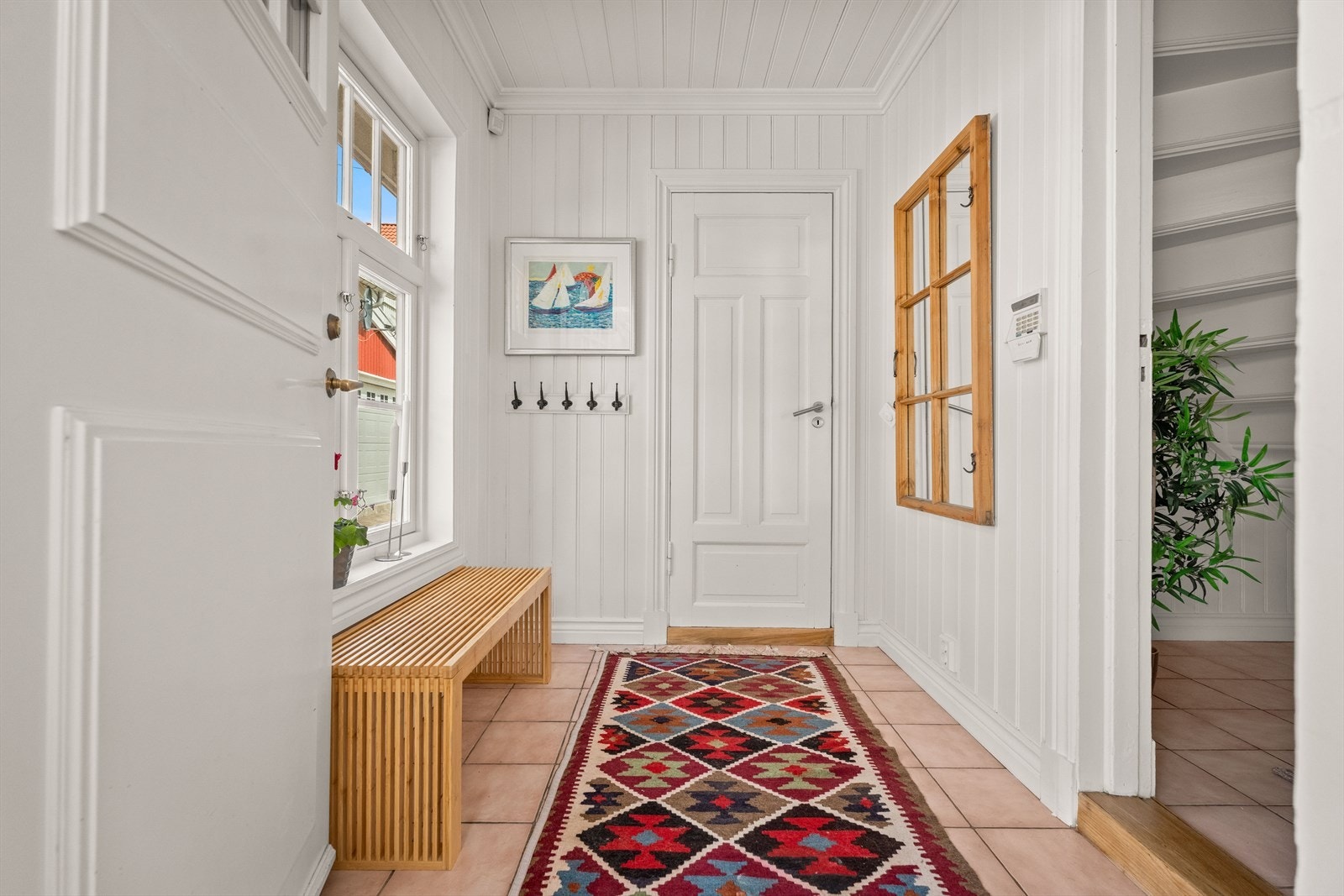 Vindfanget leder inn til en romslig hall. Gangen har flislagt gulv med elektriske varmekabler. Galleribilde