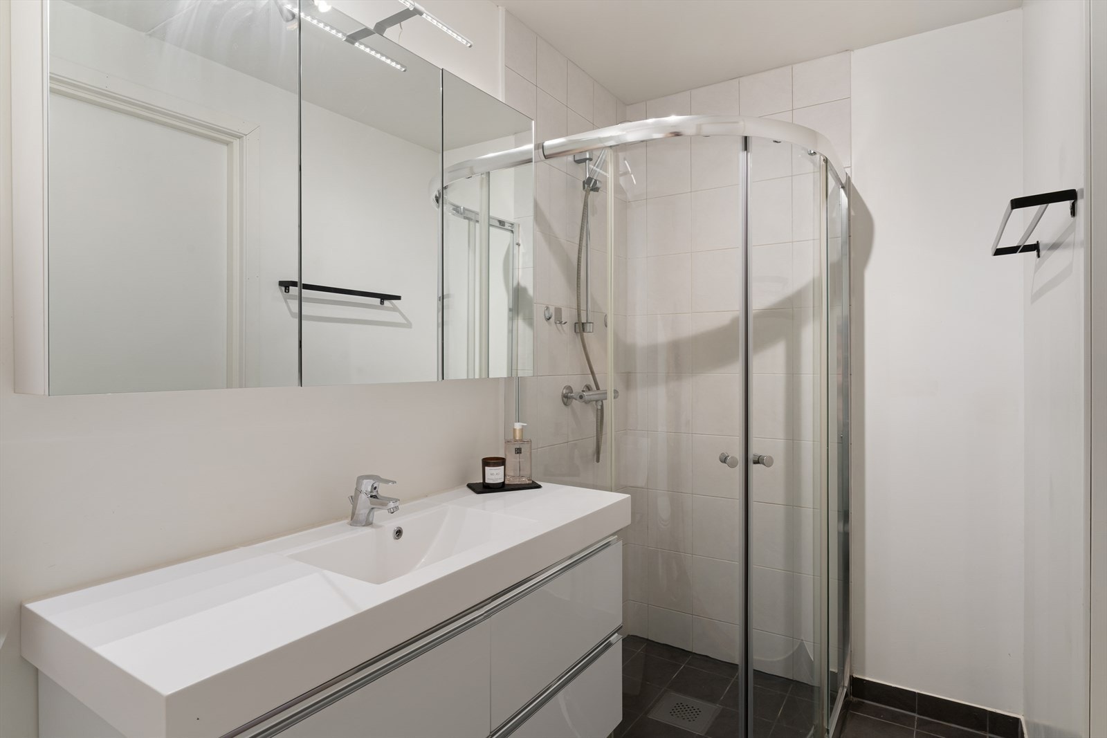 Badet er innredet med toalett, baderomsmøbel med vask og dusjhjørne. Galleribilde