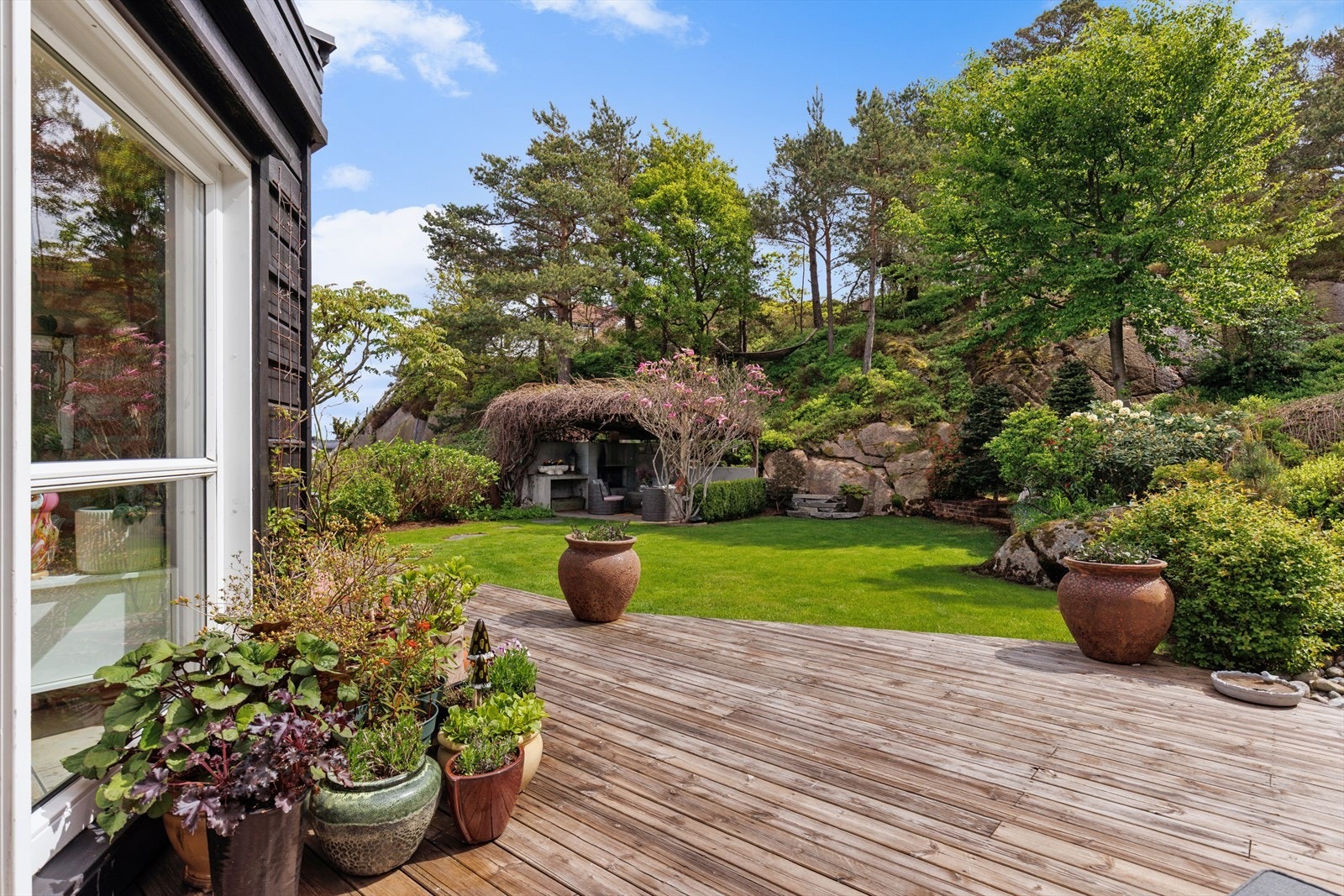 Flere uteplasser gir mulighet til å nyte solen gjennom dagen. Pergola med utepeis og drueplanter strekker seg over taket. Tomten/bakhagen grenser mot friområde, noe som gir ingen innsyn. Galleribilde