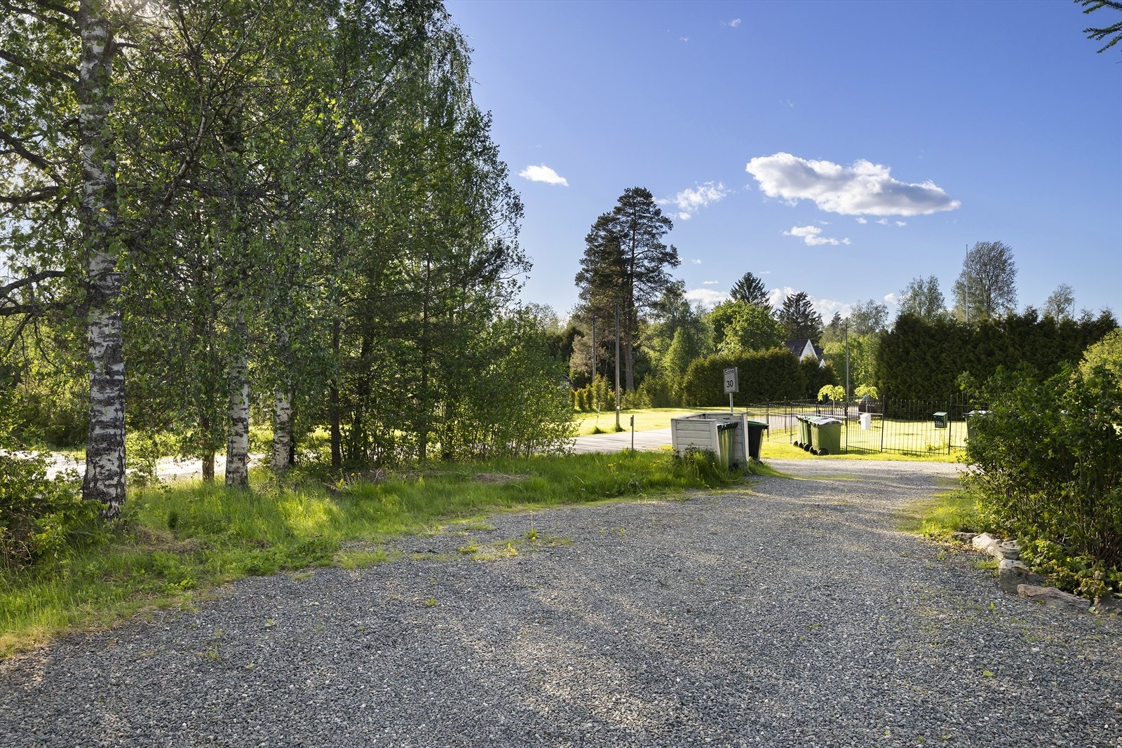 Innkjørsel med plass til flere biler. Skjermet med busjer og beplantning. Galleribilde