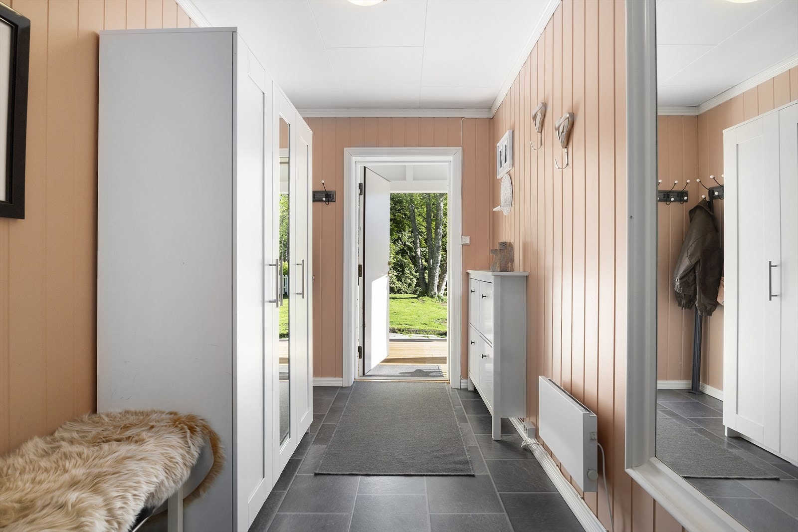 Velkommen inn! Lys og innbydende entré med oppbevaringsplass i garderobeskap og skoskap. Entreen er malt i delikat farge. Panelovn sørger for varm velkomst på kjølige dager! Galleribilde