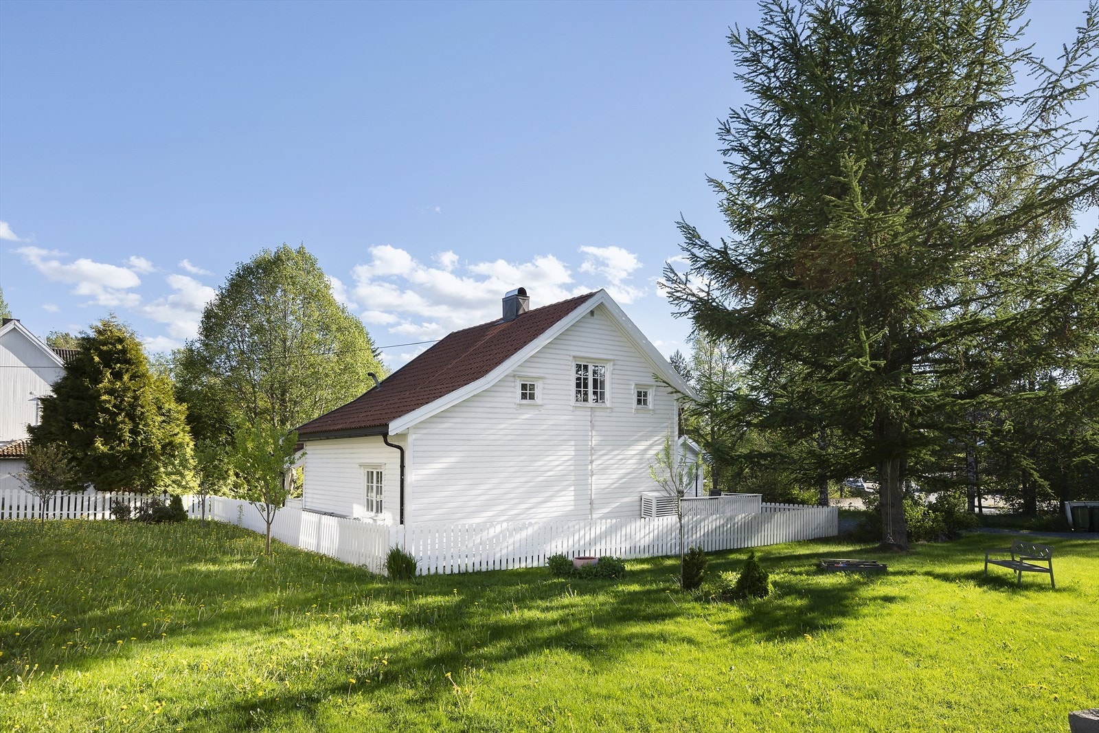 Eiendommen er inngjerdet med hvitt gjerde som står i stil til resten av boligen. Galleribilde