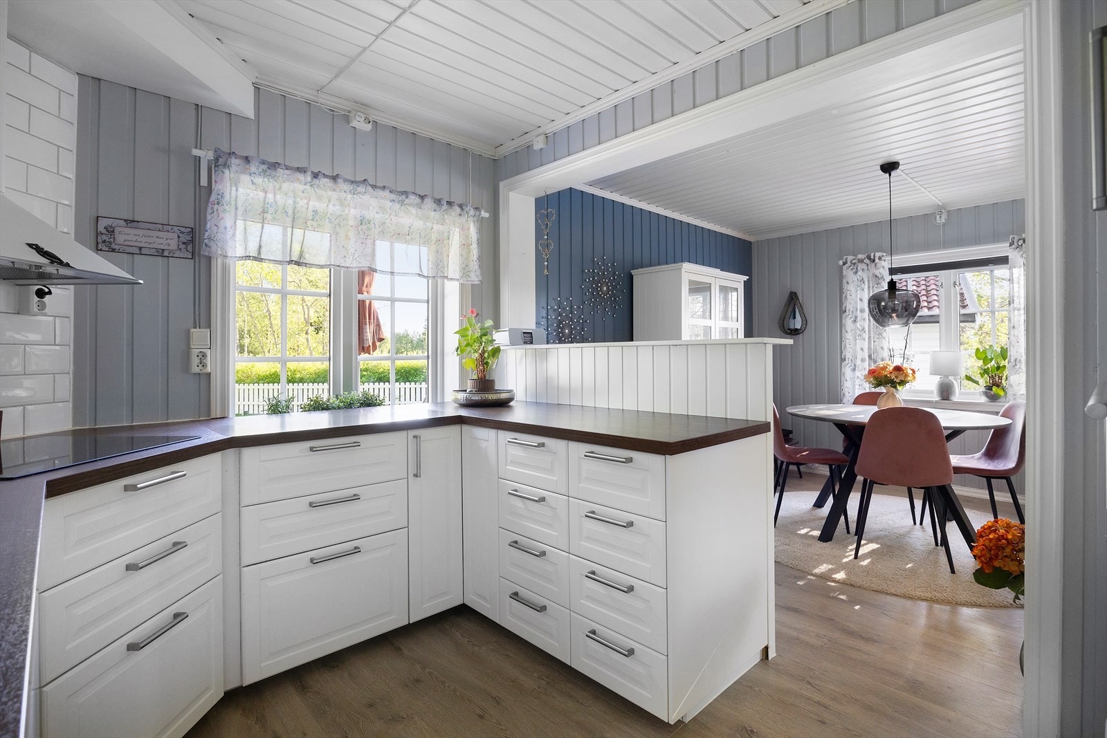 Hvite, profilerte fronter og mørk laminert benkeplate. Smart barløsning mot spisestuen. Galleribilde