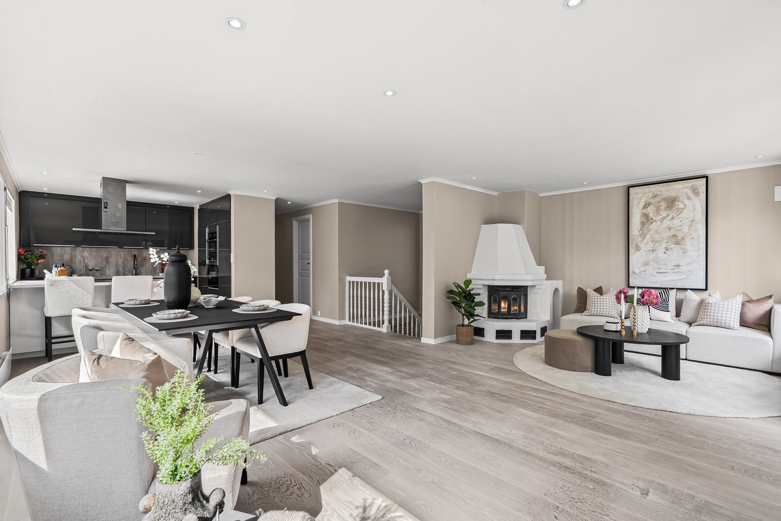 Veggene i allrommet er malt i en varm fargetone som står godt til parkettgulvet og det er ellers downlights i taket og en oppmurt peis med innsats. Galleribilde