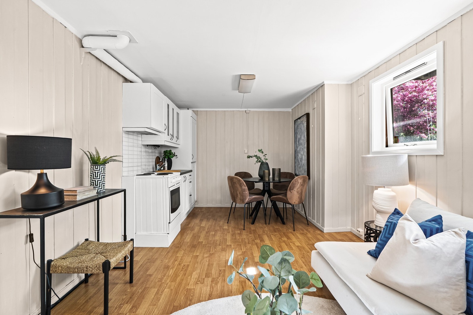 Kjøkkenet er tidløst med skap- og benkeplass, hvite fronter og grå laminatbenkeplate. Både komfyr og kjøleskap medfølger. Galleribilde