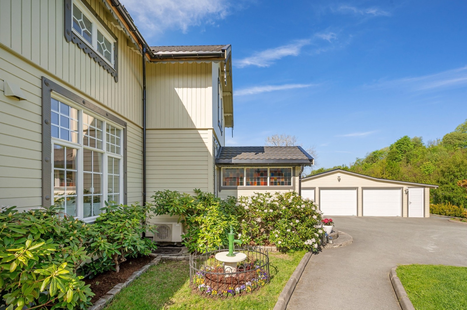 Utenfor inngangsdører finnes bl.a. flere flotte Rhododendron i ulike farger, som blomstrer vakkert i mai-juni. Galleribilde