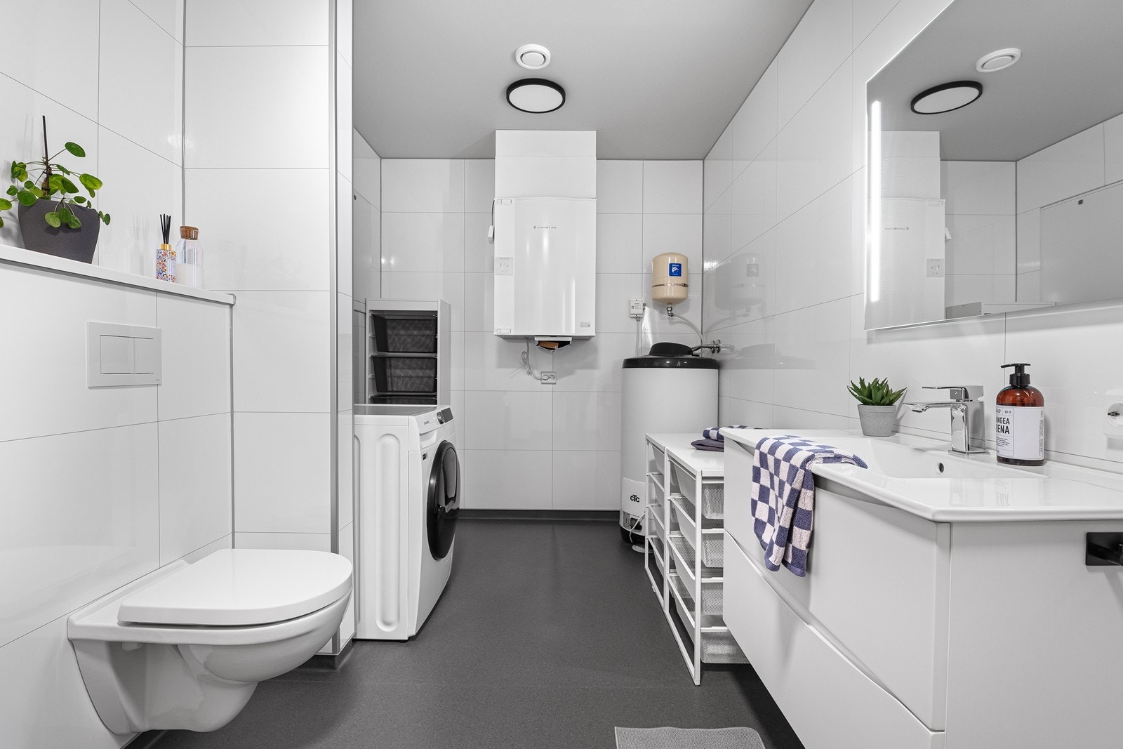 Svært romslig bad/vaskerom i 1. etasje med moderne innredning, vegghengt toalett, dusj med glassvegg og god oppbevaringsplass i servantinnredningen Galleribilde