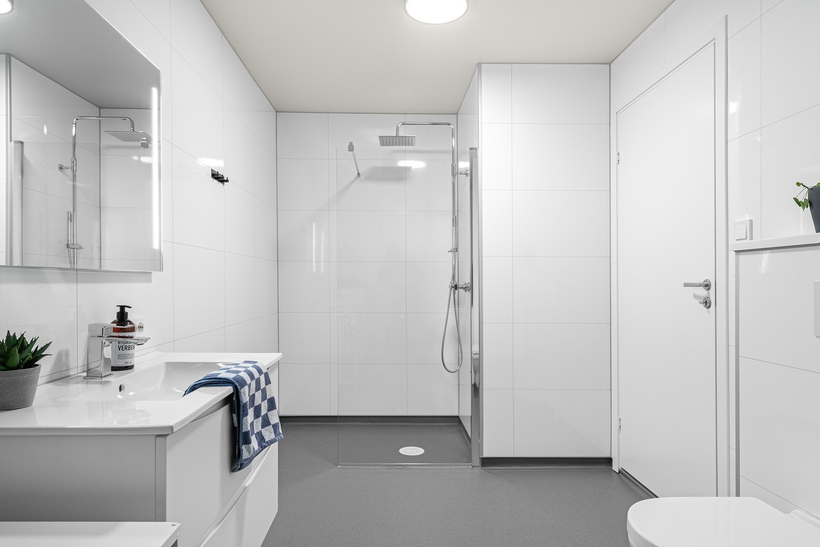 Svært romslig bad/vaskerom i 1. etasje med moderne innredning, vegghengt toalett, dusj med glassvegg og god oppbevaringsplass i servantinnredningen Galleribilde