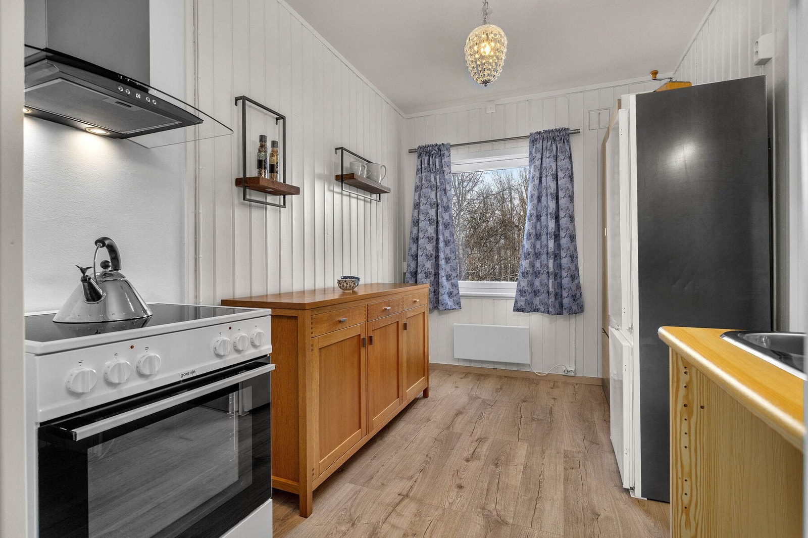 Enkel og funksjonell kjøkkenkrok med komfyr og kjøl-/fryseskap. Galleribilde