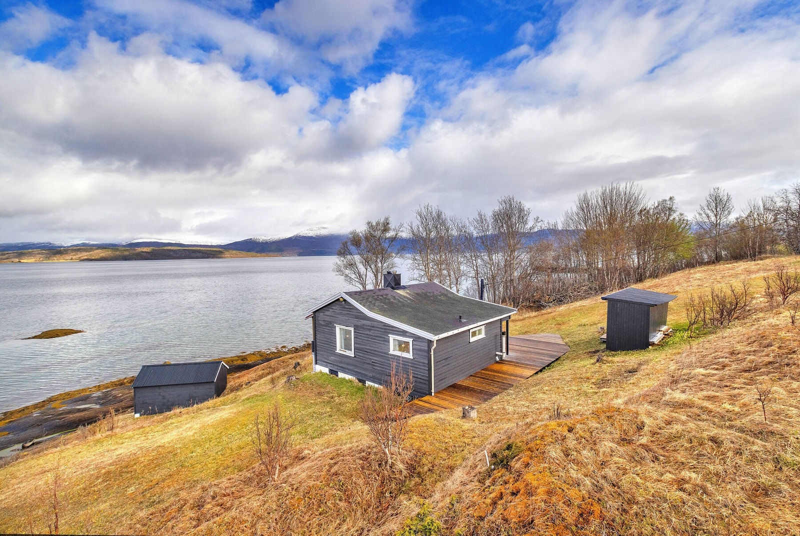 Oversikt over eiendommen med hytte, uthus og naust. Galleribilde