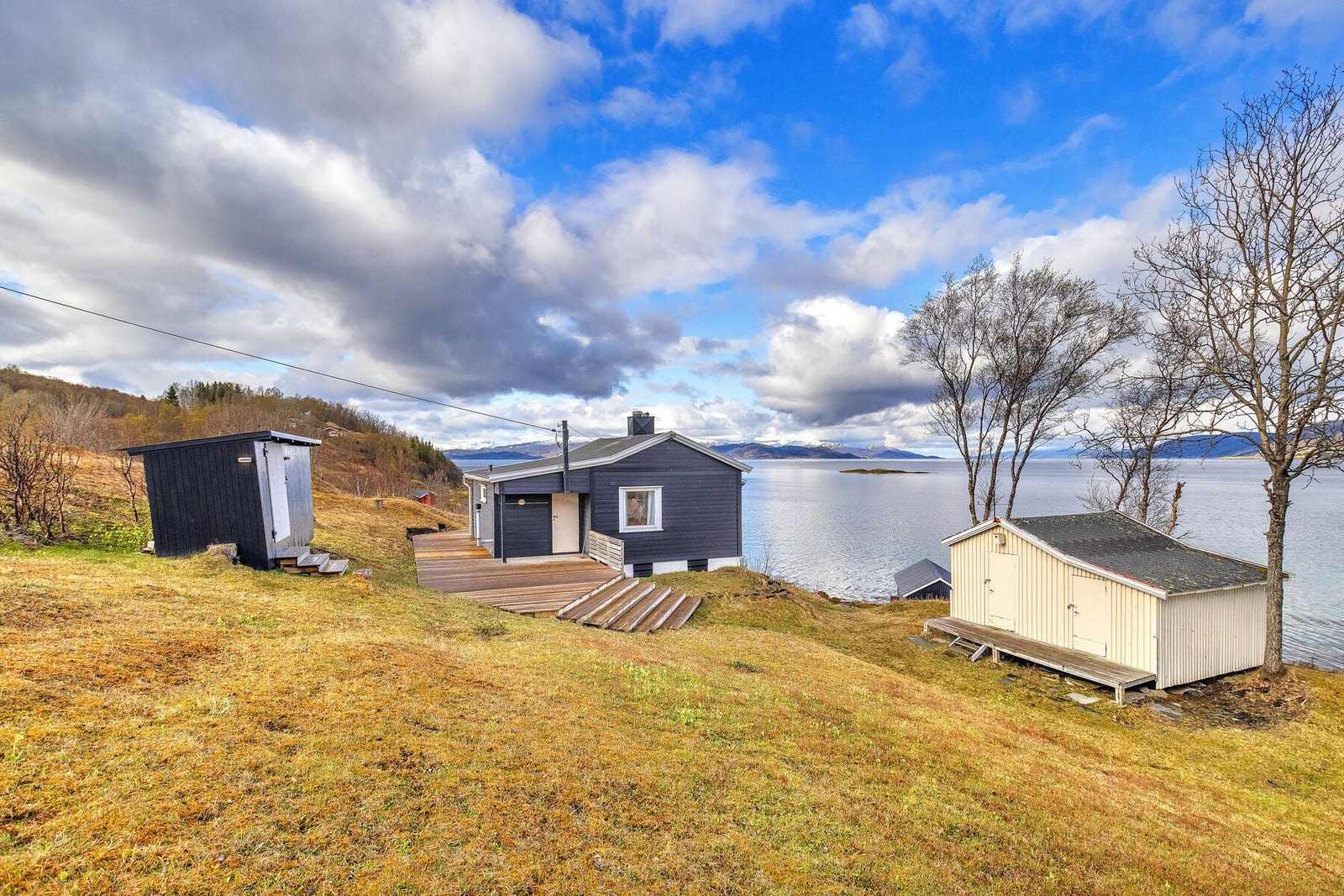 Hytta og de tilhørende bygningene sett fra tomten. Galleribilde