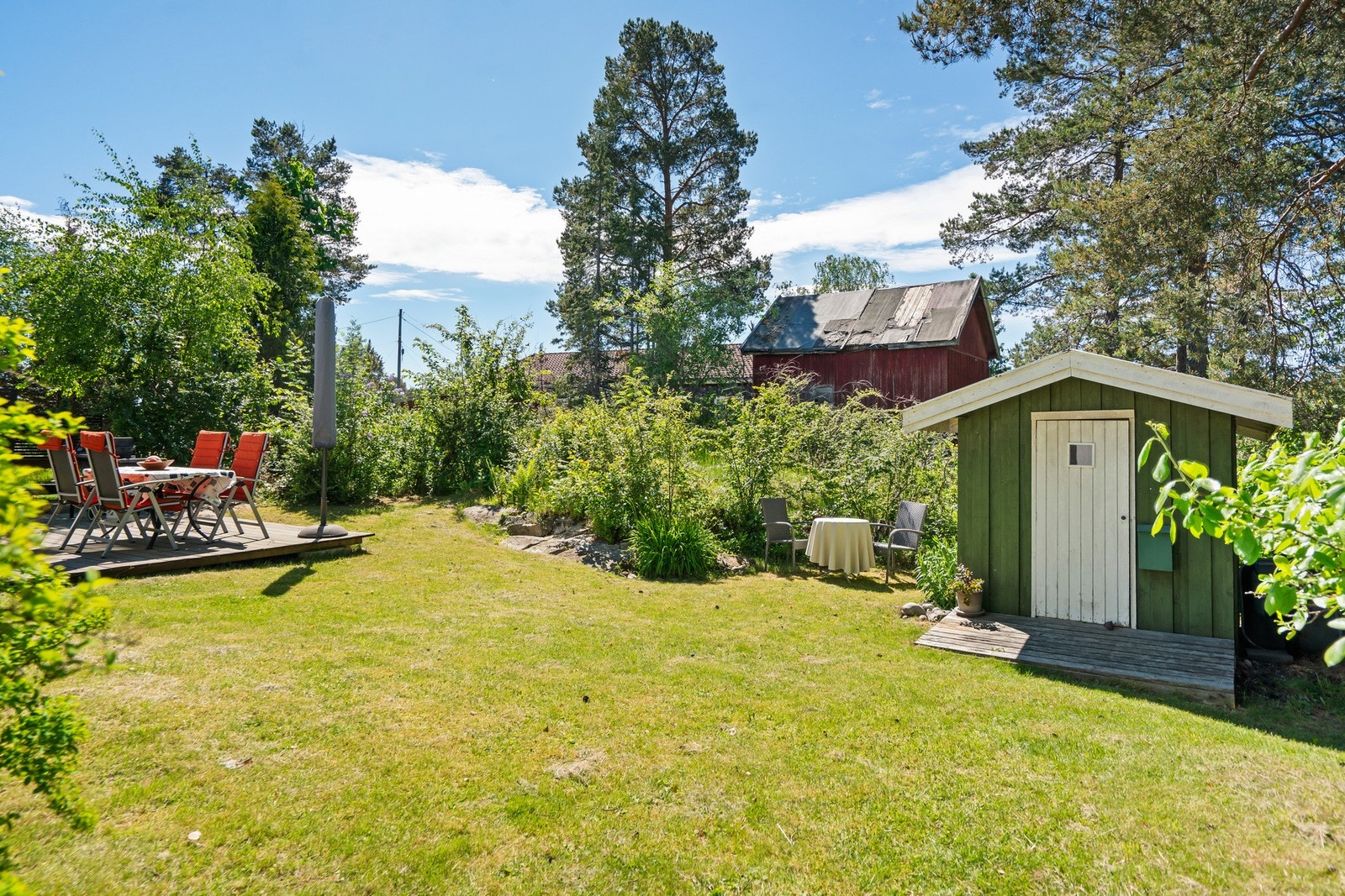 Pen, opparbeidet hage med gressplen og beplantning med et lite uthus. Galleribilde