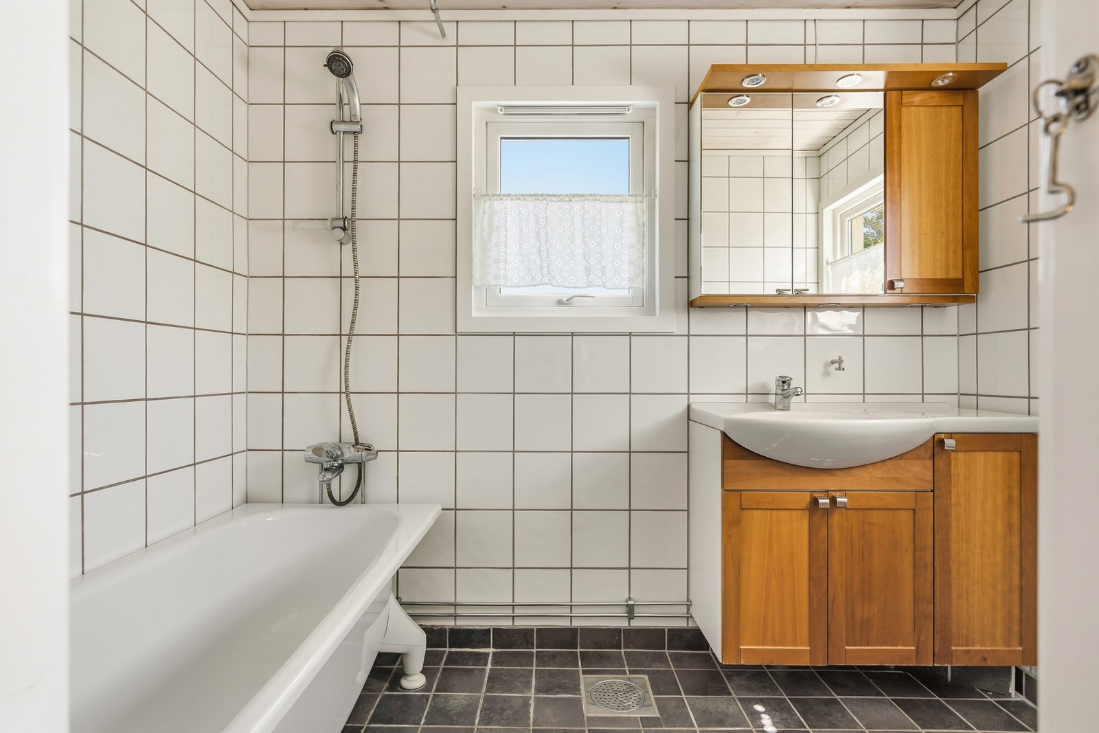 Pent flislagt bad fra 2006 innredet med badekar, servant med underskap, speilskap og wc. Galleribilde