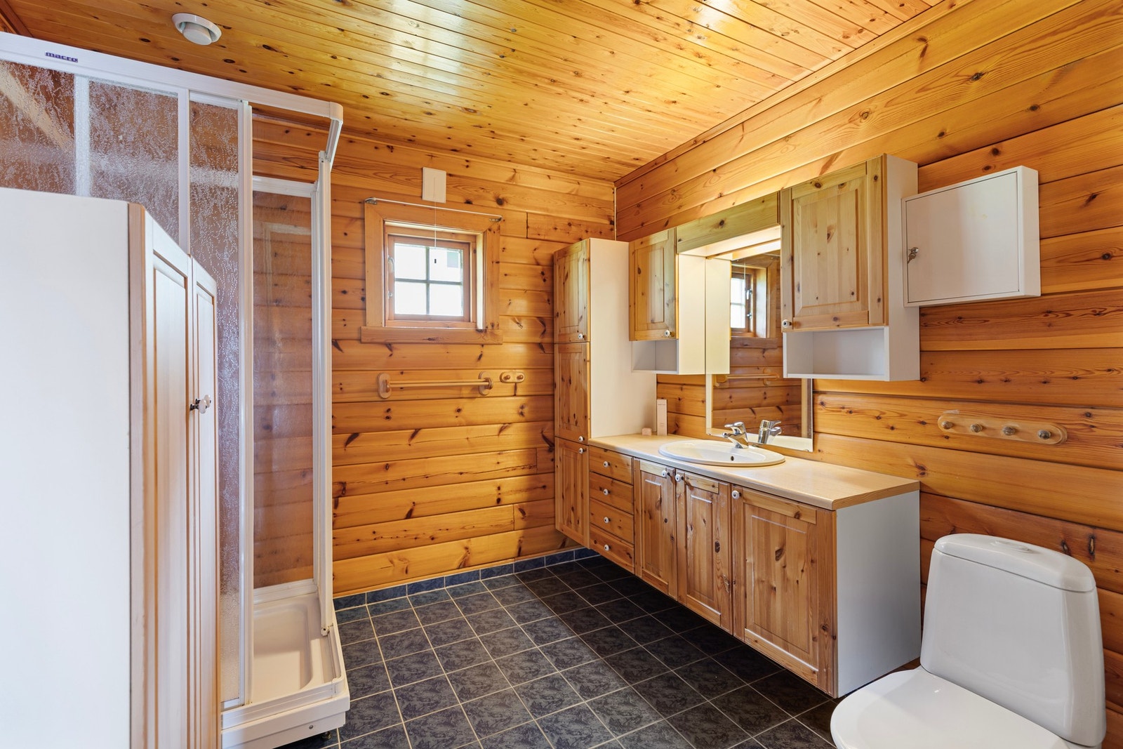 Badet er utstyrt med dusjkabinett, servantinnredning og toalett. Galleribilde