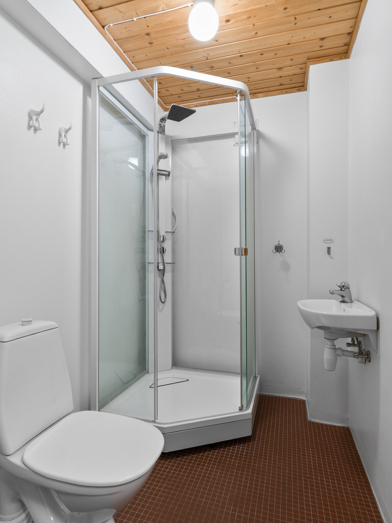 Badet i underetasjen har fliser på gulv og malt våtromstapet på veggflatene. Badet er utstyrt med servant, toalett og dusjkabinett. Galleribilde