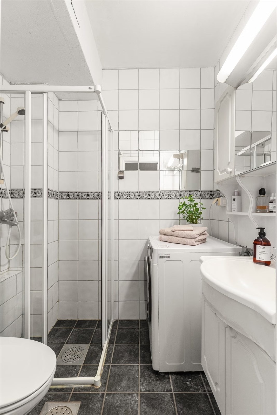 Badet har innredning med servant og overskap, opplegg for vaskemaskin, dusjhjørne og toalett. Galleribilde