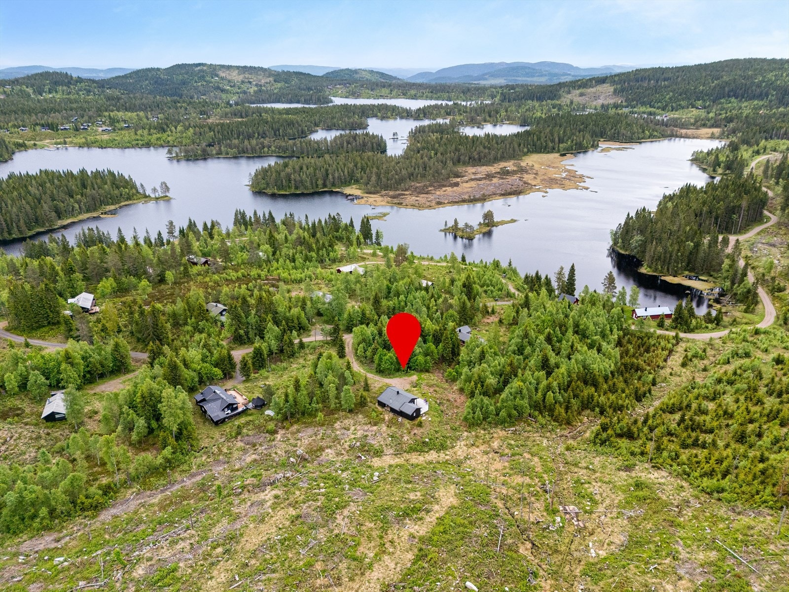 Et idyllisk hytteområde med flere vann og skog så langt øyet kan se. Galleribilde