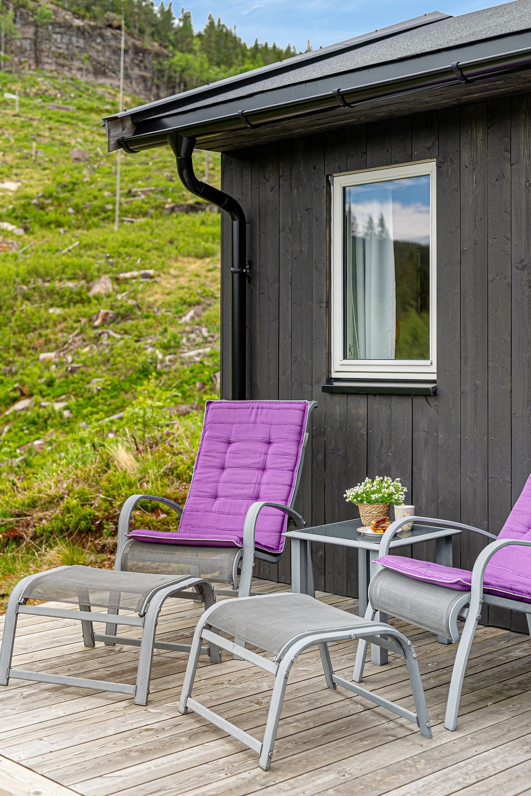Hytta har en mørkbeiset trekledning som står godt til den omkringliggende naturen. Galleribilde