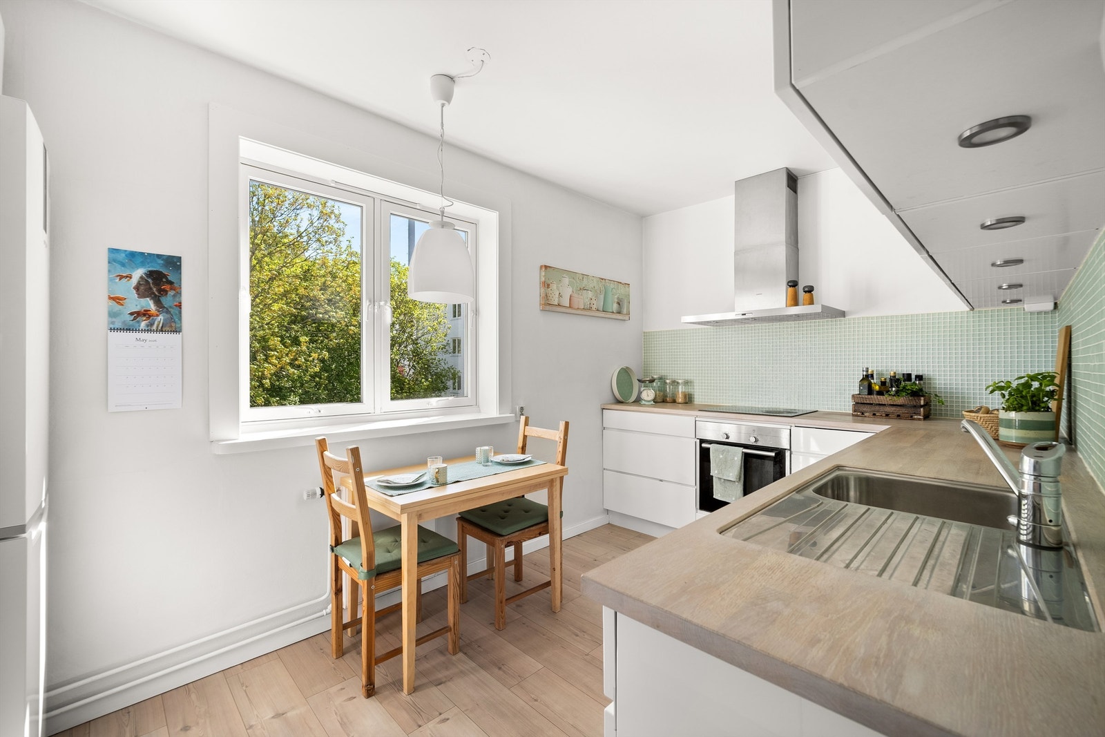 Kjøkkenet har benkeplate i tre som gir varme til rommet og står fint til de lyse flatene og den delikate mosaikkflisen mellom benk og overskap. Galleribilde