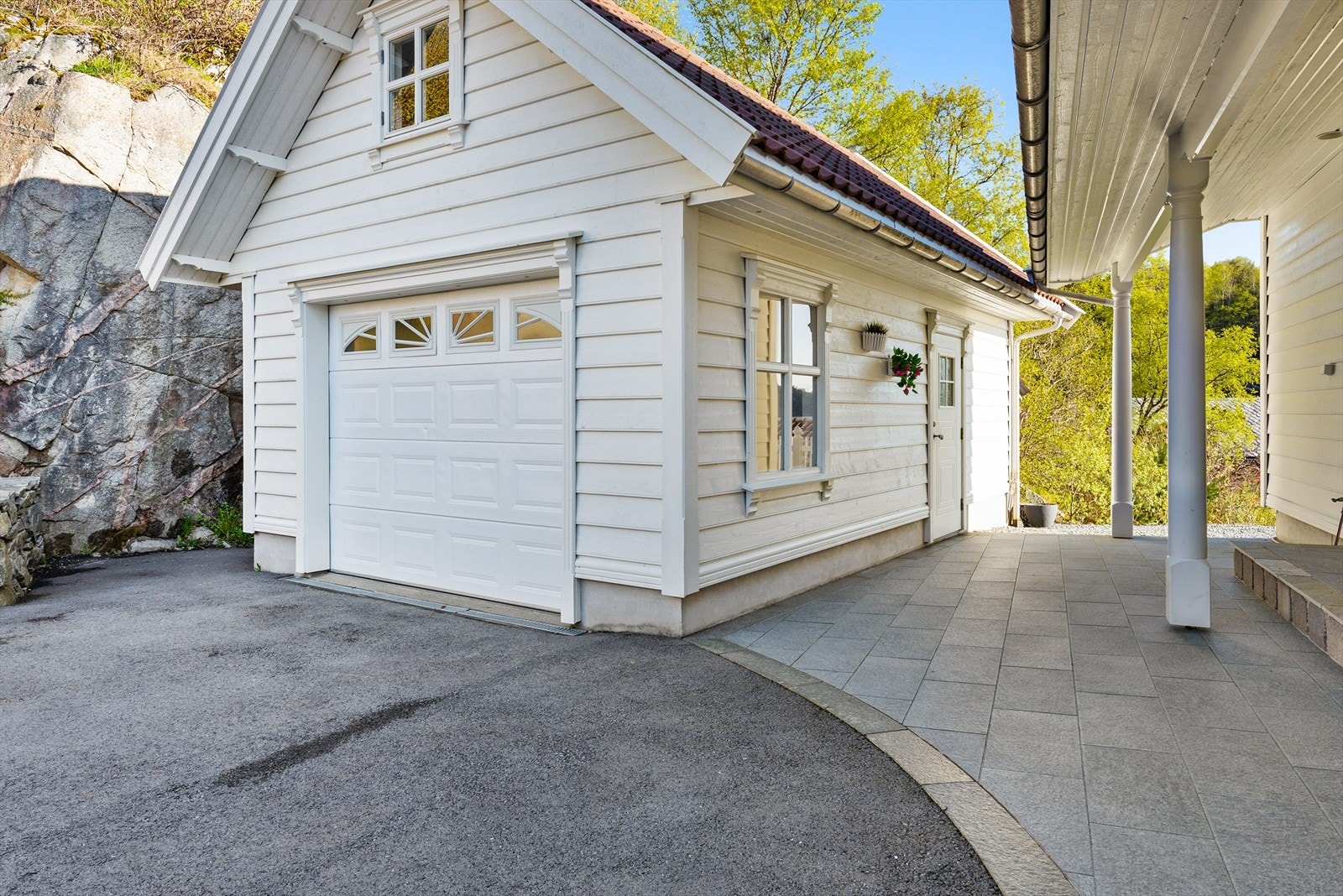 Garasje med leddport og elektrisk åpner. Bygningen har saltak tekket med betongstein. Galleribilde