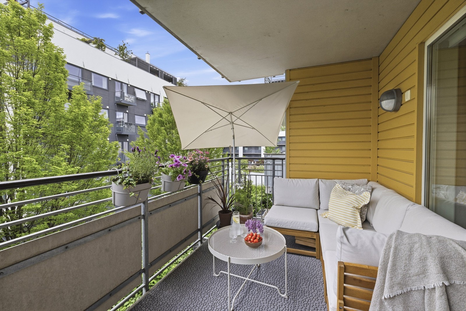Adkomst fra stue til balkong. Solrik balkong på 9 m² med utsikt mot grønne fellesområder. Selger opplyser om sol på balkongen fra formiddag (kl. 9/10) til kveld på sommeren Galleribilde