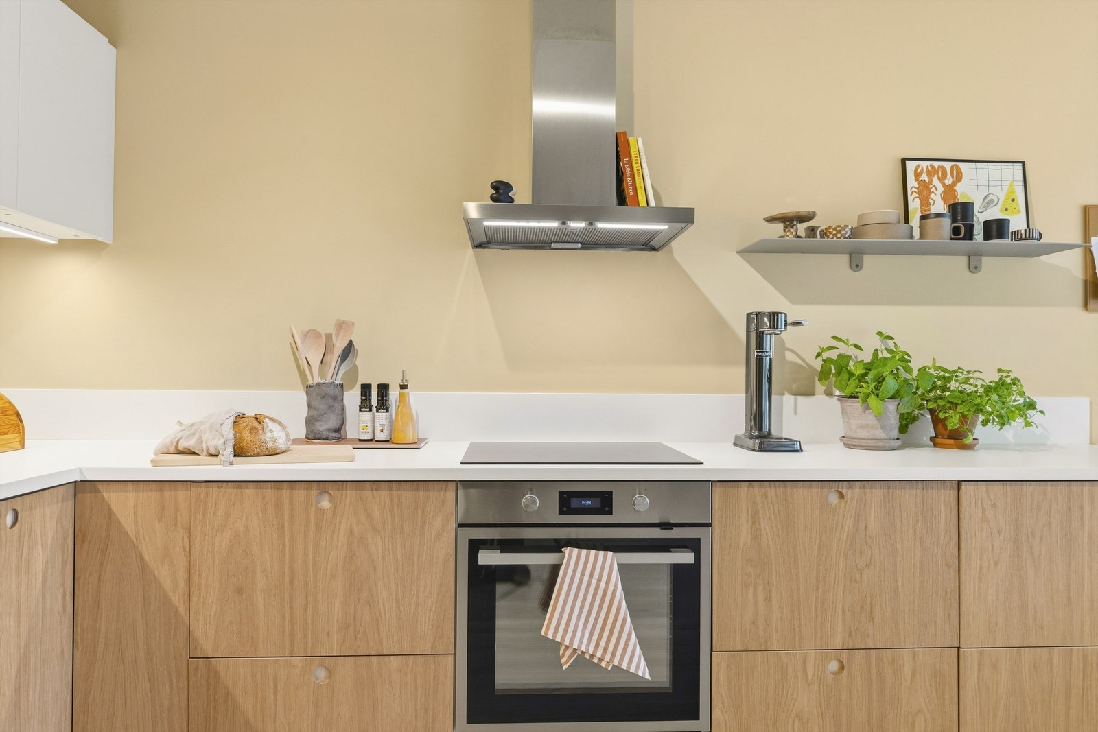Stilrik kjøkkeninnredning fra 2023 med glatte eikefronter og benkeplate med laminert overflate. Skrog fra IKEA og fronter fra Noremax Galleribilde