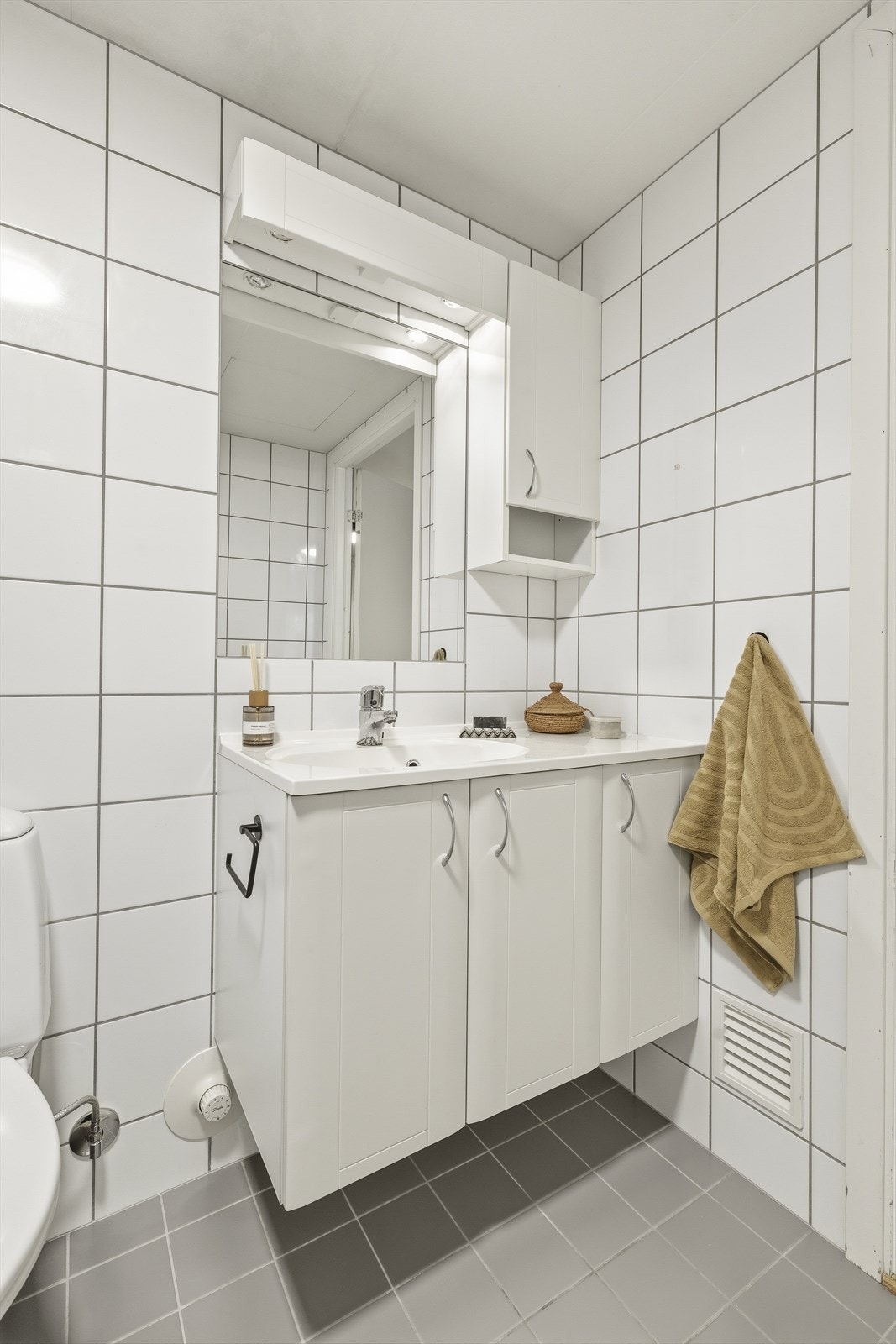 Badet består av vegghengt servantinnredning, speil med overlys, dusjhjørne med dører, vegghengt dusjarmatur og vegghengt toalett Galleribilde