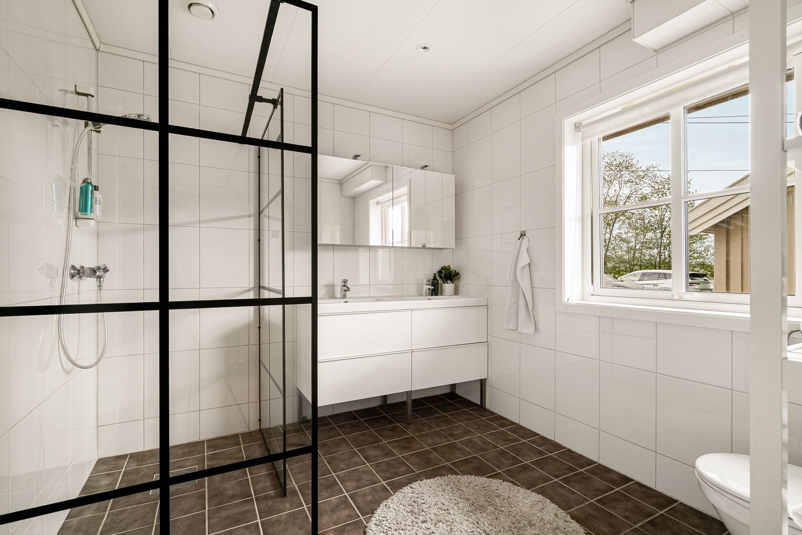 Lyst, flislagt baderom med moderne dobbel servantinnredning, romslig dusjhjørne og toalett, samt downlights i himlingen. Galleribilde