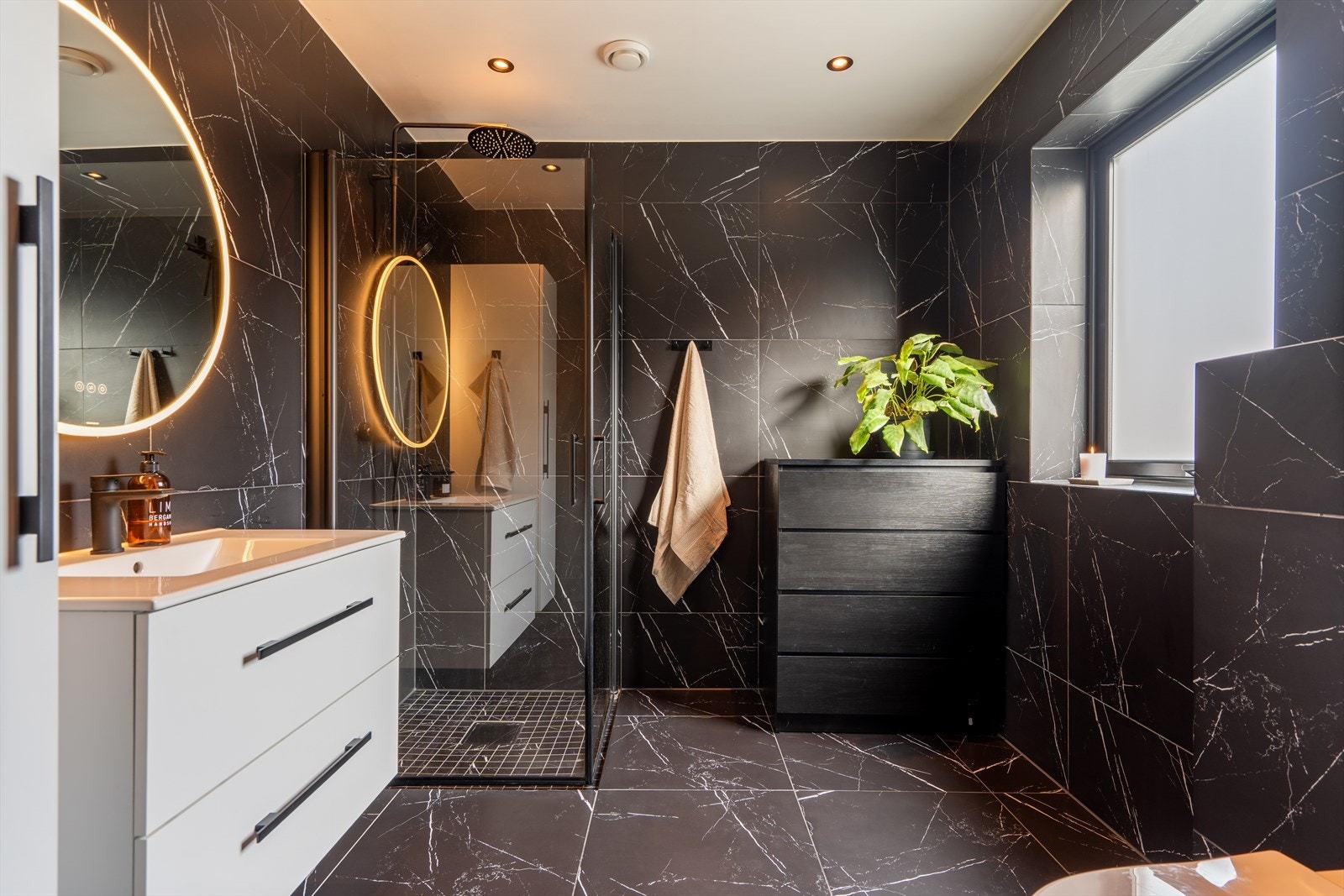 Badet i 1. etasje er romslig, moderne og pent innredet med helflisede overflater, heldekkende servant, vegghengt toalett og dusjløsning med dusjdører. Galleribilde
