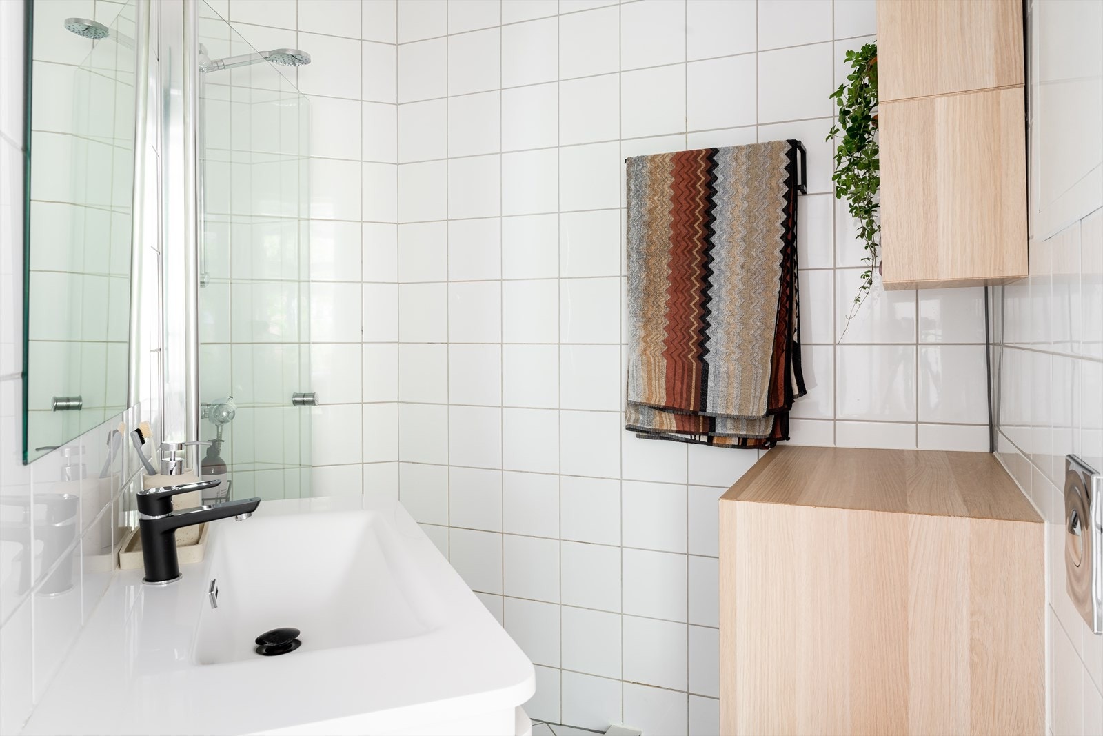 Badet inneholder vegghengt toalett, dusjdører i glass og opplegg for vaskemaskin. Galleribilde