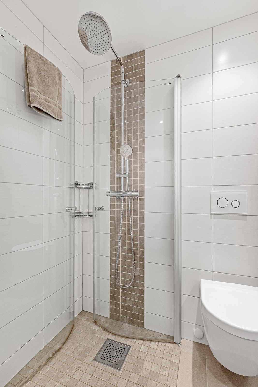 Badet er utstyrt med vegghengt toalett og dusjhjørne med glassdører. Rør-i-rør-system fra 2015. Galleribilde