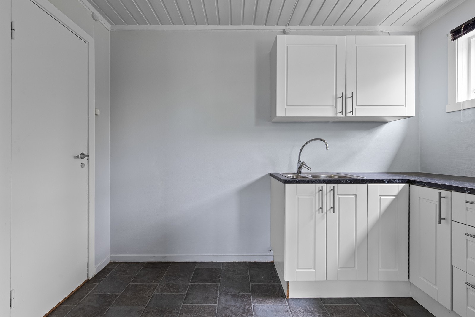 Kjøkkeninnredning i hvit utførelse med profilerte fronter og laminat benkeplate i underetasje. Galleribilde
