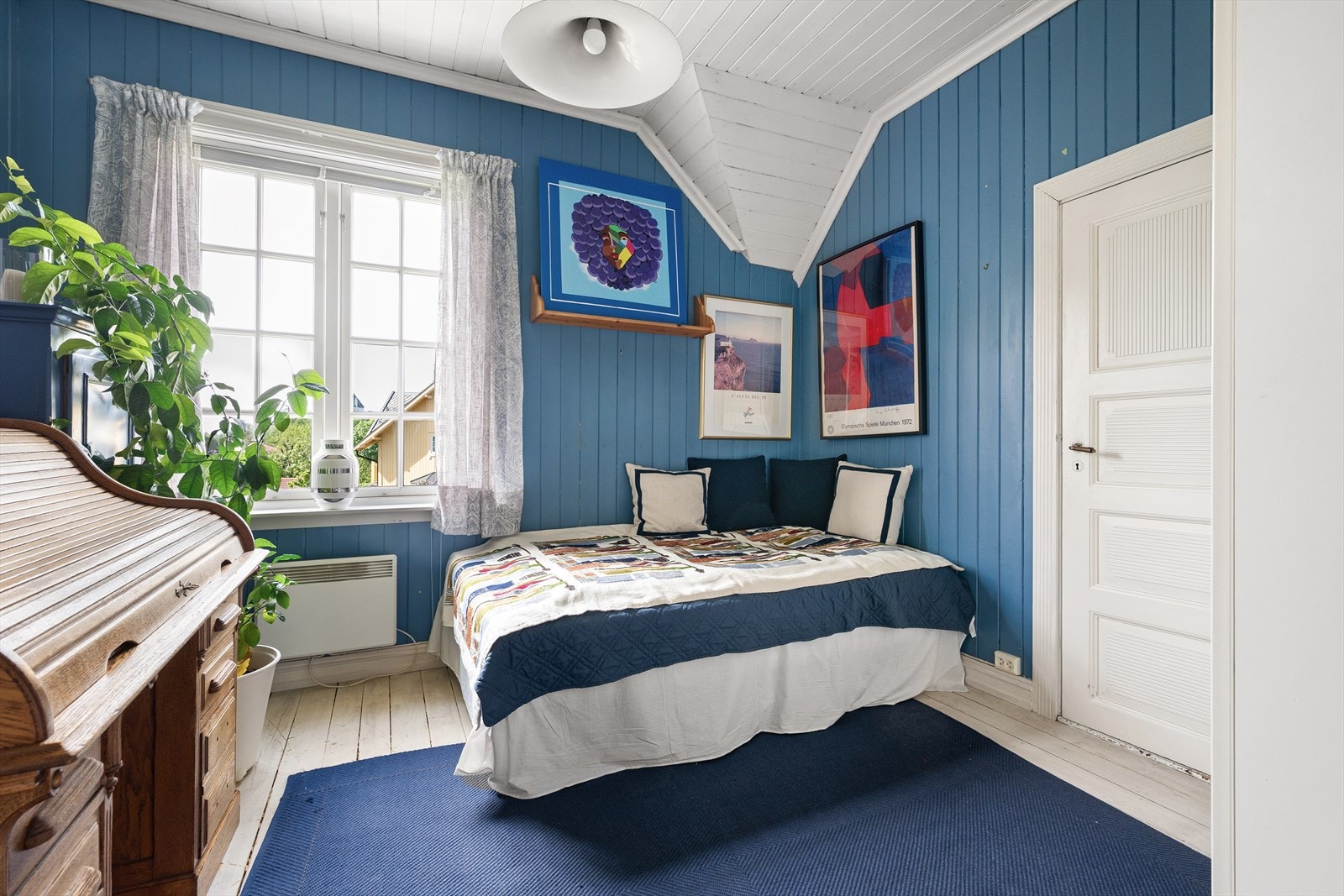 Et av etasjens fire soverom, med malt furugulv og panel på veggene. Galleribilde