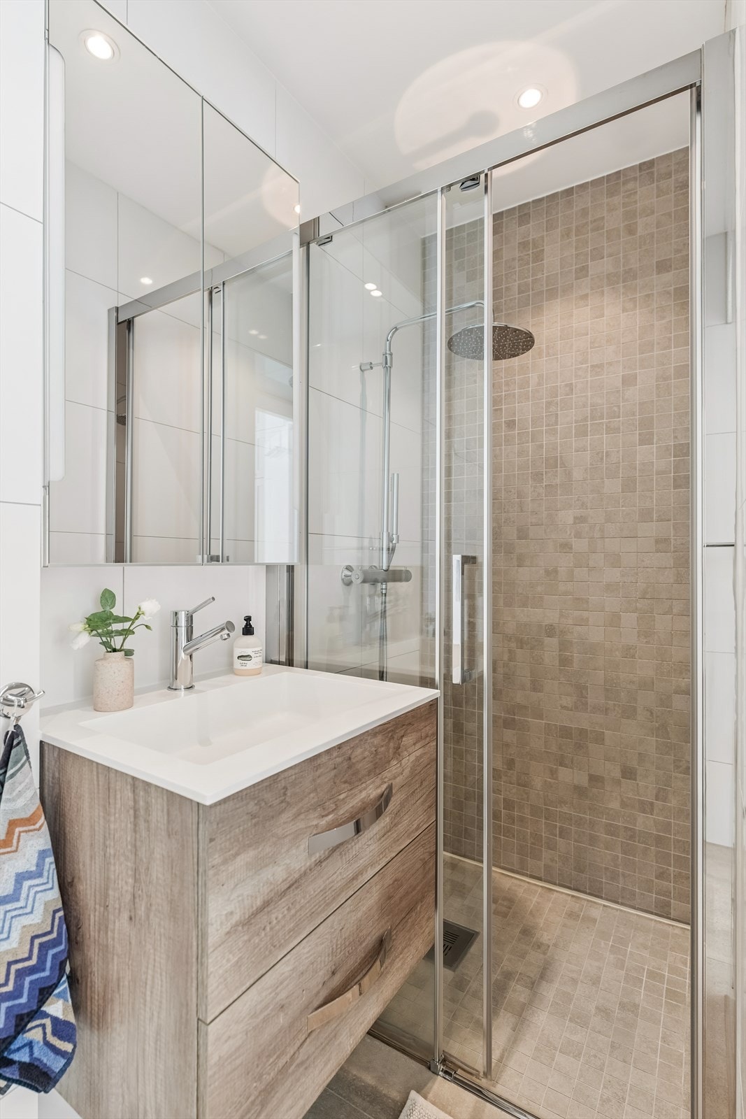 Innredningen består av servant med skuffeseksjon, speilskap med belysning over servant og vegghengt toalett. Videre har badet en dusjsone med skyvedør i glass. Galleribilde
