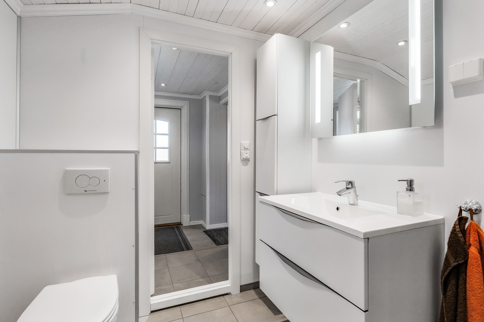 Badet er innredet med servant med underskap, speil med lys, skap, dusjhjørne, vegghengt WC, og opplegg for vaskemaskin. Galleribilde