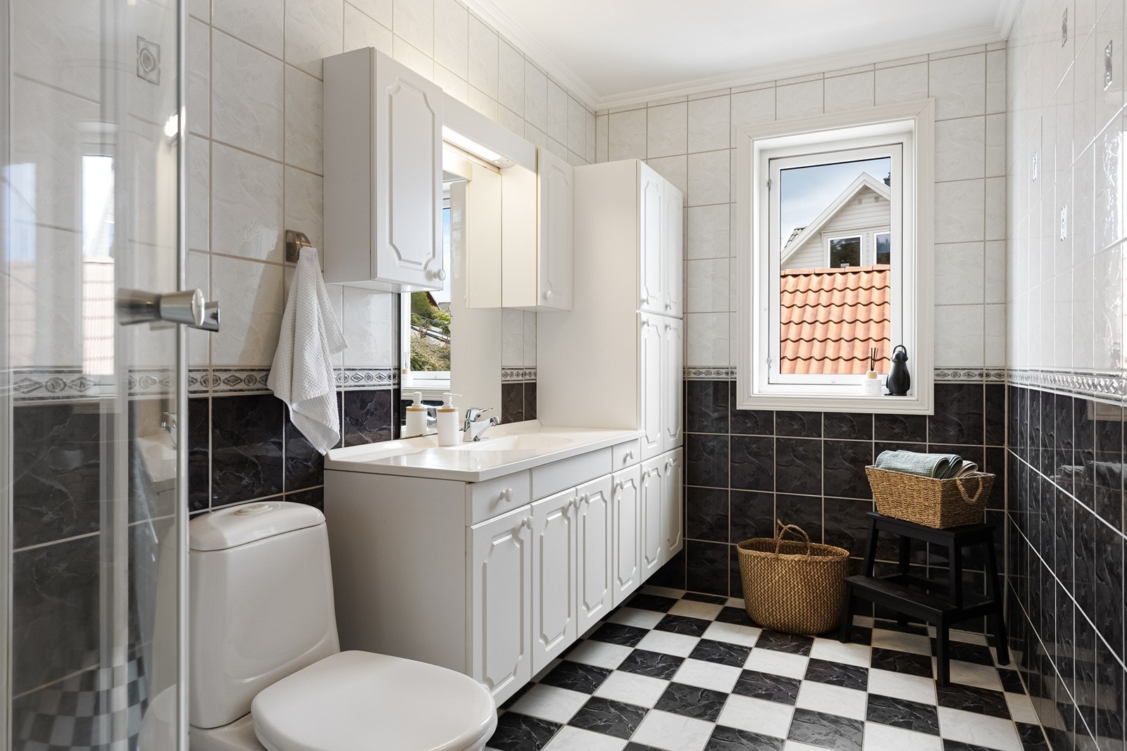 Praktisk bad med servant med skap og speil, wc og dusjkabinett. Badet har flislagte gulv og vegger Galleribilde
