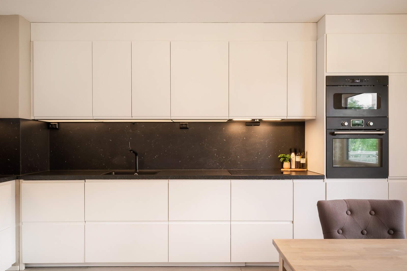 Kjøkkenet har innredning bestående av slette, hvitfolierte skrog, underlimt oppvaskkumme og laminert benkeplate. Galleribilde