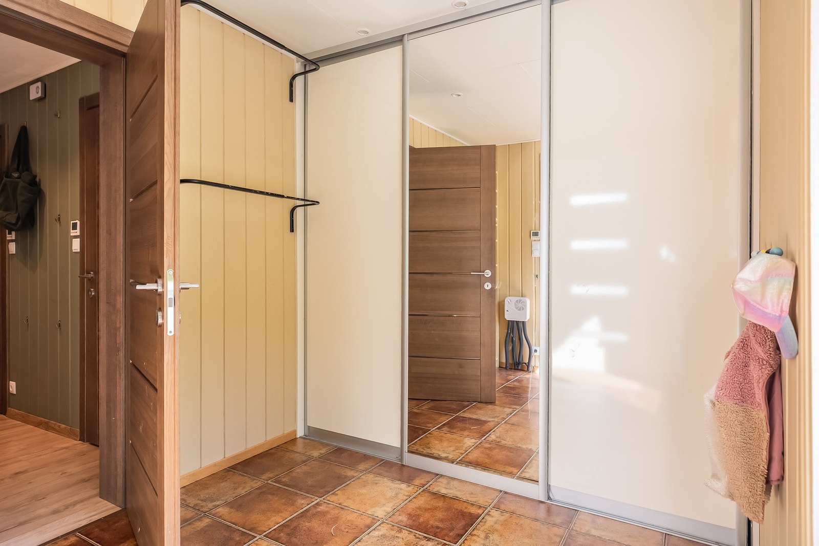 Romslig entré med flislagt gulv og gulvvarme fra Veria. Her er det etablert praktisk skyvedørsgarderobe med god oppbevaringsplass. Galleribilde