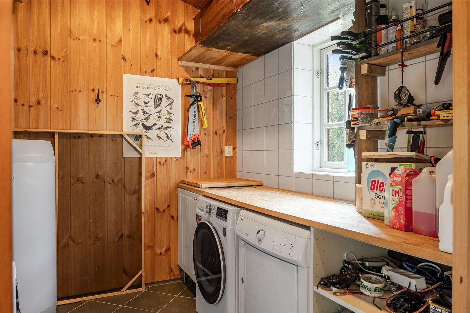 Vaskerommet er innredet med praktisk benk, hyller og underskap, og har flislagt gulv med sluk. Galleribilde