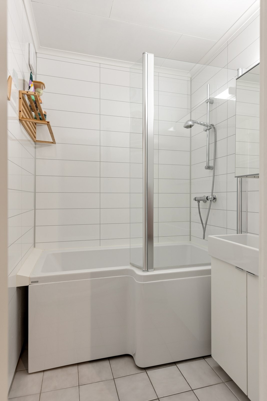 Lyst og pent bad med flislagt gulv og varmekabler. Utstyrt med badekar med dusj og servant med innredning. Mekanisk ventilasjon. Galleribilde