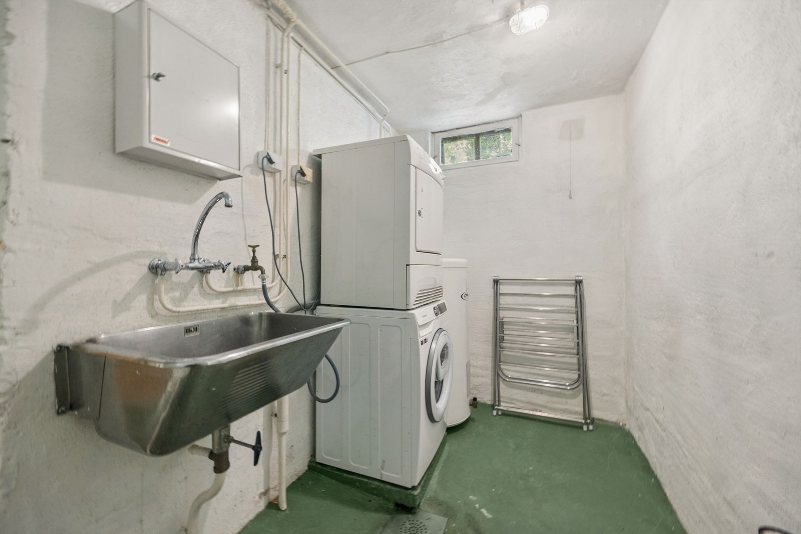 Separat vaskerom med enkel standard fra byggeår. Gulv og vegger i malt mur. Rommet er praktisk plassert og har plass til vaskemaskin, tørketrommel og oppbevaring. Galleribilde