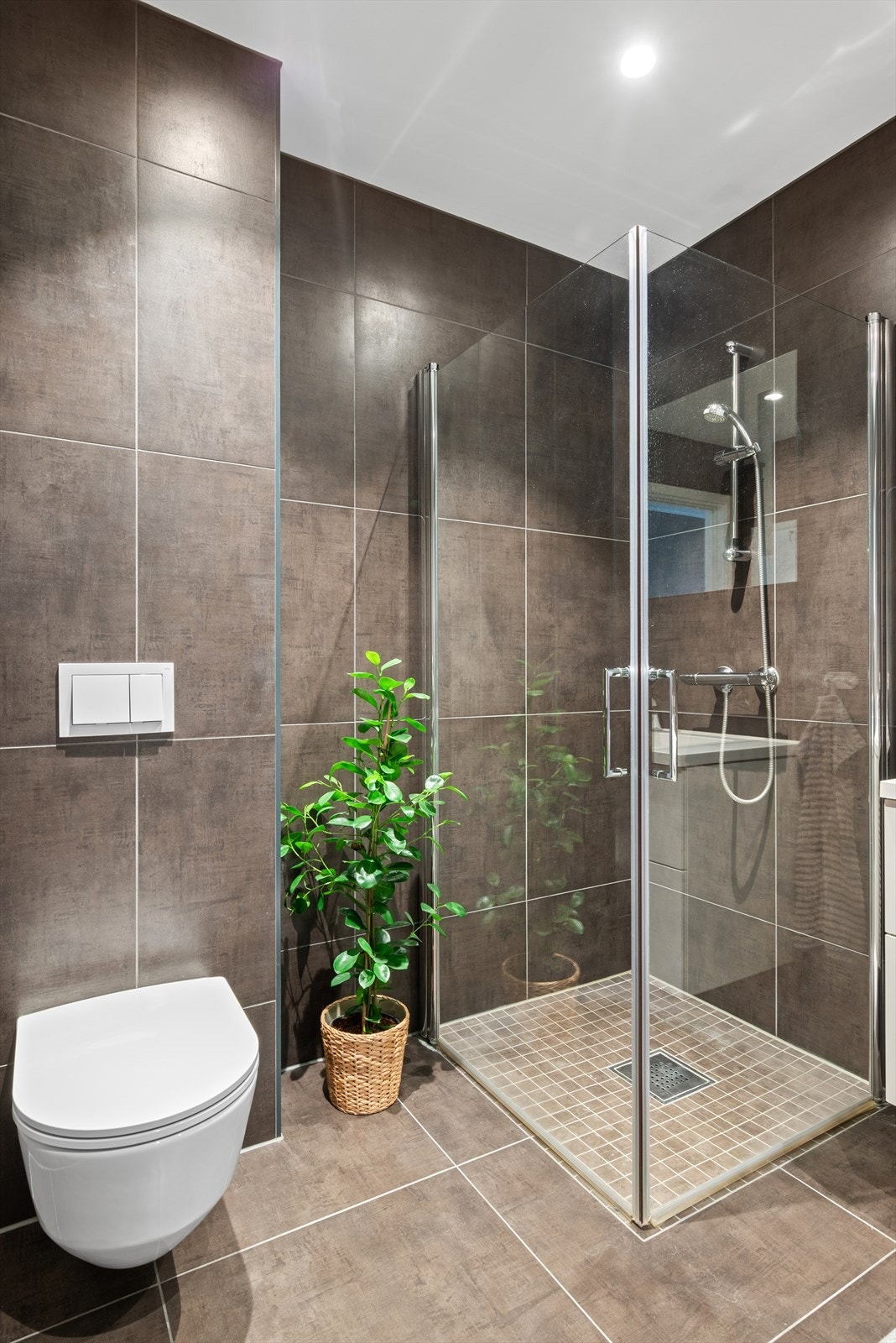 Badet har varmekabler i gulv, praktiske innfellbare dusjdører, vegghengt toalett og opplegg for vaskemaskin. Galleribilde