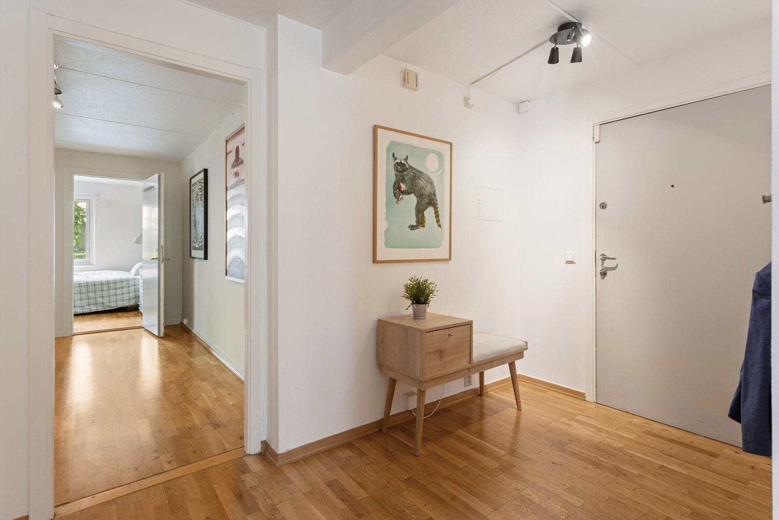 Romslig entré med parkett på gulv som leder videre inn i leiligheten. Galleribilde