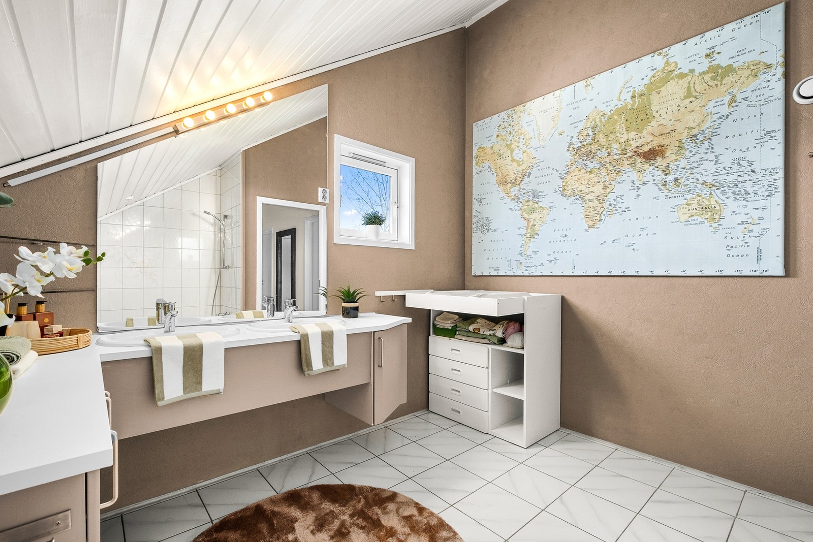 Badet er innredet med servantinnredning, speil og overlys, gulvmontert toalett og badekar. Galleribilde