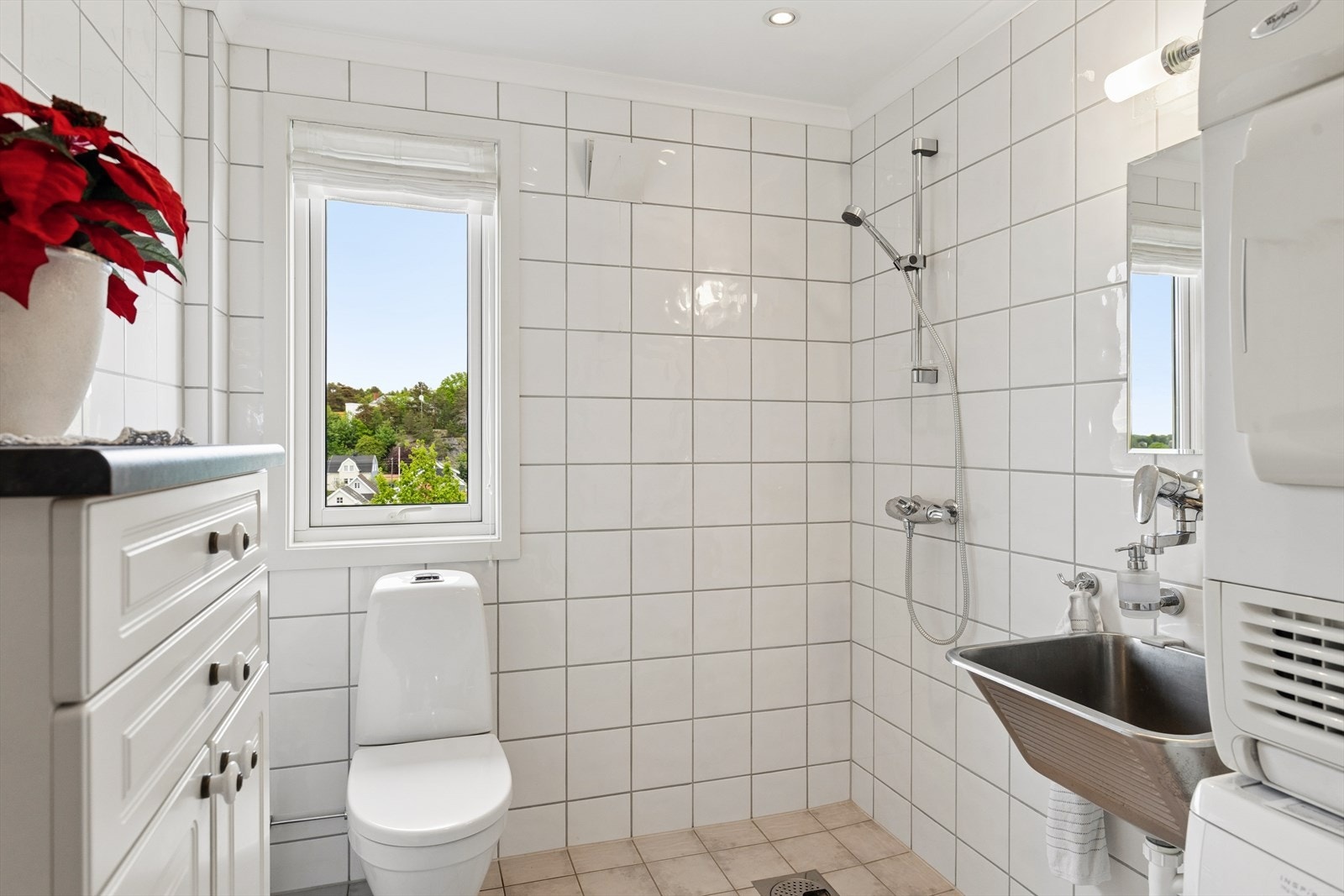 Praktisk vaskerom/bad med fliser på gulv og vegger, opplegg for vaskemaskin og tørketrommel. Galleribilde