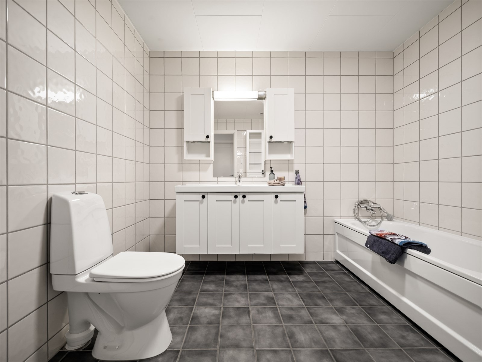 Flislagt bad med varmekabler i gulv og god planløsning. Utstyrt med toalett, baderomsinnredning med nedfelt servant, speil med belysning samt overskap og høyskap. Galleribilde
