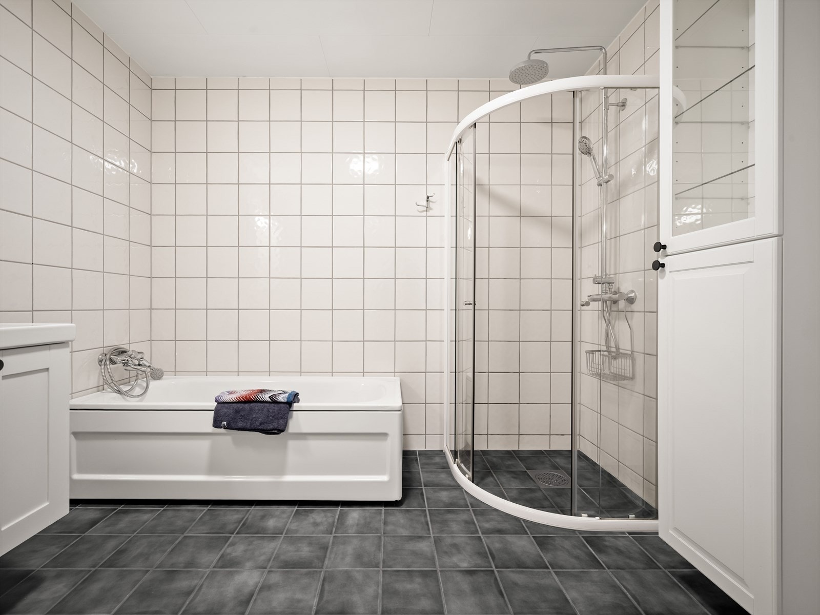Badet har både badekar og dusjløsning med dusjvegger. Flislagte overflater gir et tidløst uttrykk, og rommet har balansert ventilasjon. Galleribilde