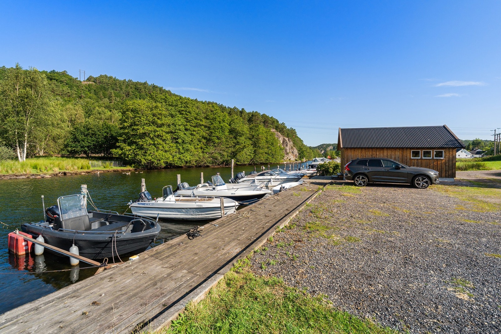 Lundeelva med brygge, sjøbod og parkering like ved. Galleribilde