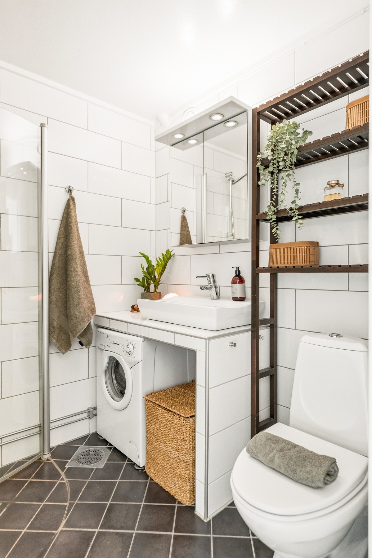 Pent baderom med et tidløst uttrykk, flislagte overflater og behagelig gulvvarme. Badet har en plassbygget, flislagt innredning. Galleribilde
