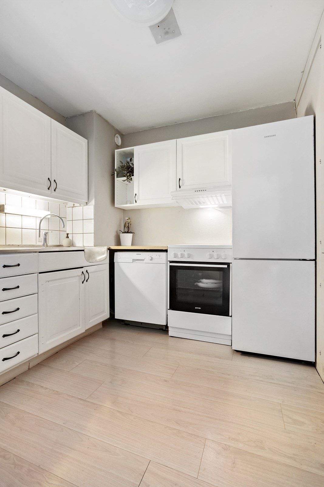 Kjøkkeninnredning med profilerte fronter og benkeplate i laminat og rustfritt stål. Galleribilde